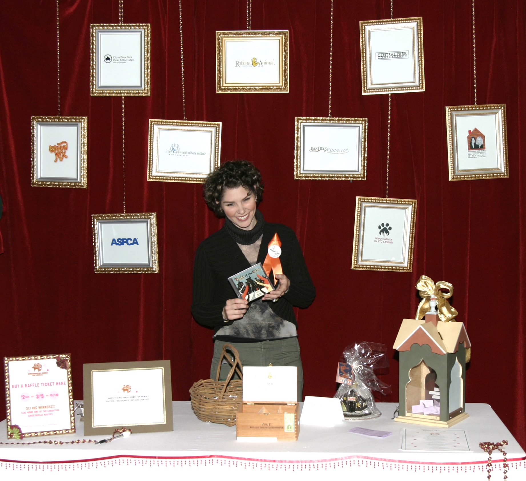 Event organizer at the sponsors and raffle table with framed partner logos on red velvet backdrop